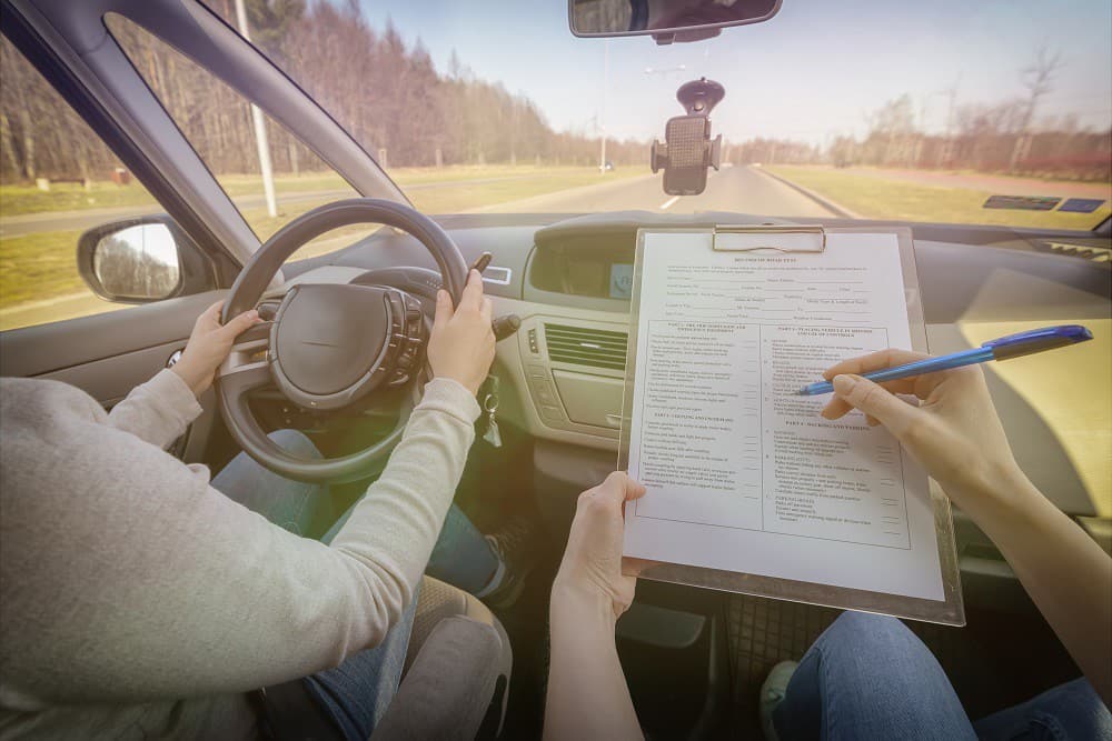 Examinador rellenando la hoja de la prueba dentro del coche, durante un examen práctico